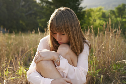 woman curled up in a field