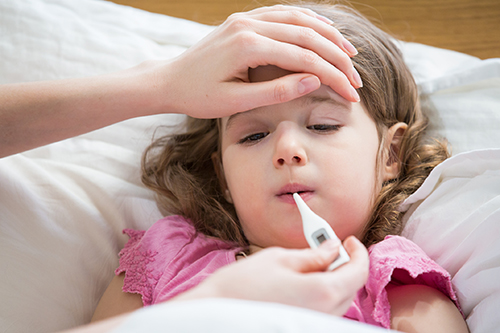 parent taking temperature of sick little girl