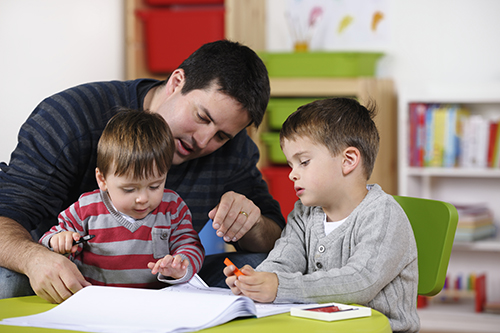 dad helping two sons draw
