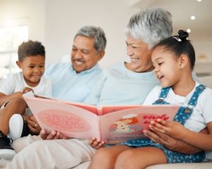 Grandma and grandpa sitting with their grandkids reading a book
